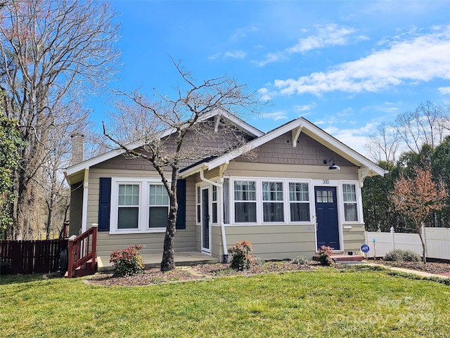 view of front of house featuring entry steps, a front yard, and fence