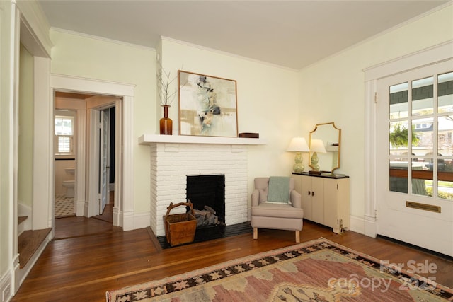 living area with a fireplace, ornamental molding, and wood finished floors