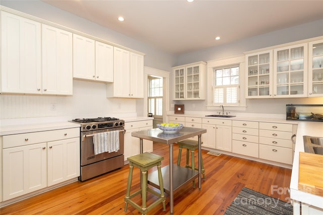kitchen featuring light countertops, recessed lighting, stainless steel range with gas cooktop, a sink, and light wood-style flooring