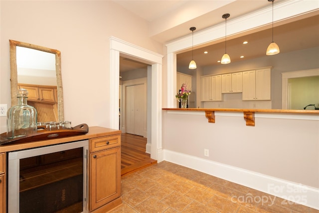 kitchen featuring a breakfast bar area, recessed lighting, wine cooler, baseboards, and pendant lighting