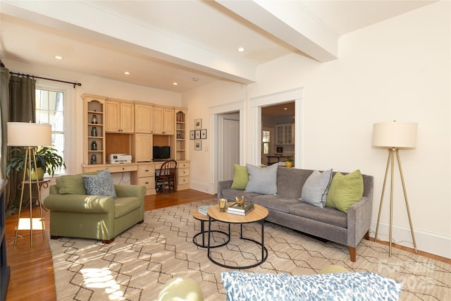 living area featuring baseboards, built in study area, light wood-type flooring, and beam ceiling