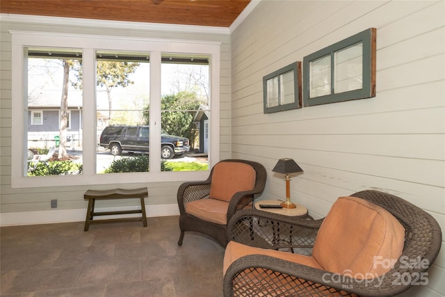 sitting room featuring a wealth of natural light, crown molding, and wood walls