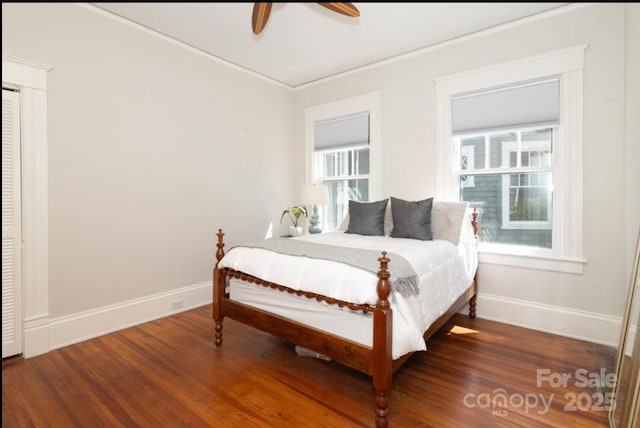 bedroom featuring baseboards, wood finished floors, multiple windows, and a ceiling fan