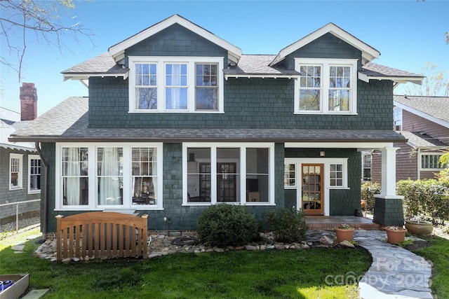 shingle-style home featuring covered porch and roof with shingles