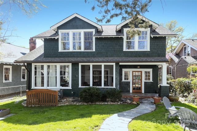shingle-style home with a front lawn, a chimney, and a shingled roof