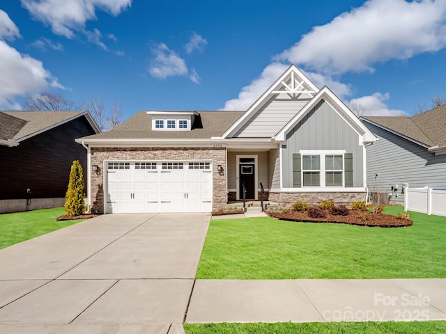 craftsman house featuring board and batten siding, a front yard, a garage, stone siding, and driveway