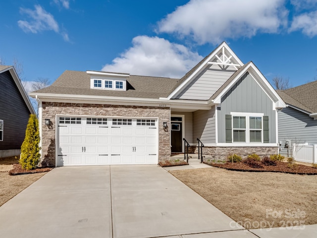 craftsman-style home with a shingled roof, concrete driveway, stone siding, an attached garage, and board and batten siding