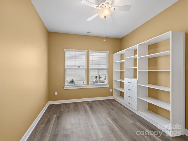 unfurnished room with ceiling fan, wood finished floors, visible vents, and baseboards