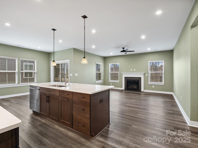 kitchen with dishwasher, dark wood-style floors, a fireplace with flush hearth, light countertops, and a sink