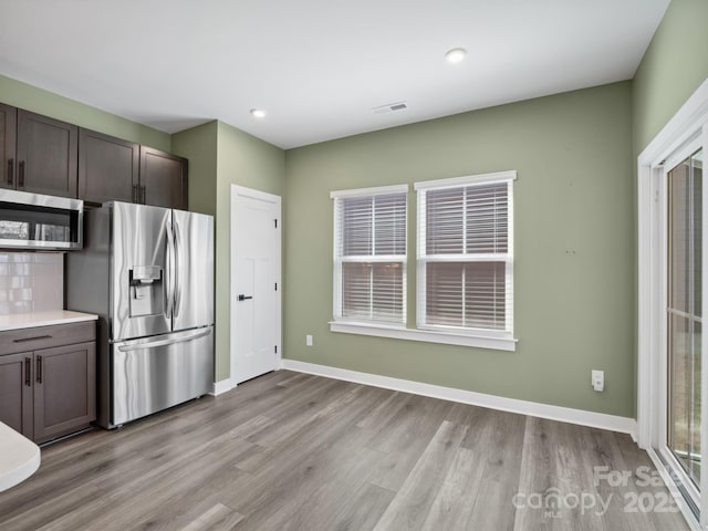 kitchen with dark brown cabinetry, stainless steel appliances, visible vents, baseboards, and light wood-type flooring