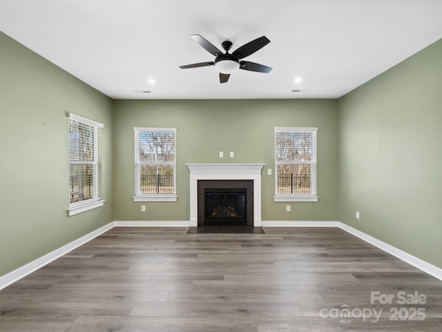 unfurnished living room with baseboards, a wealth of natural light, and wood finished floors