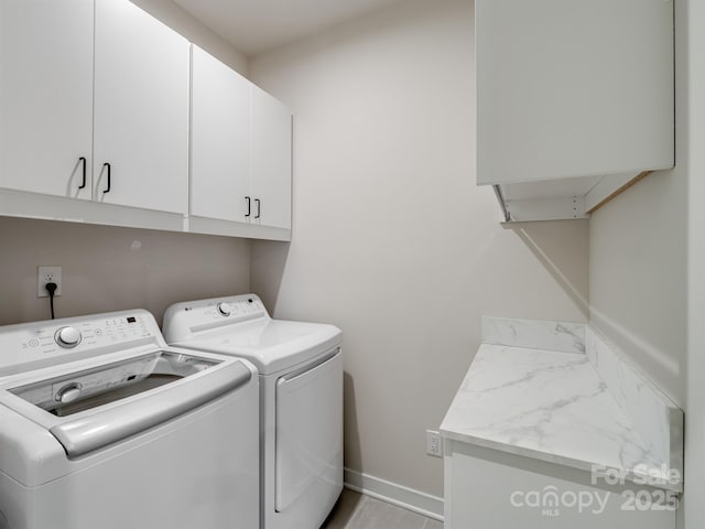 laundry room with washing machine and dryer, cabinet space, and baseboards