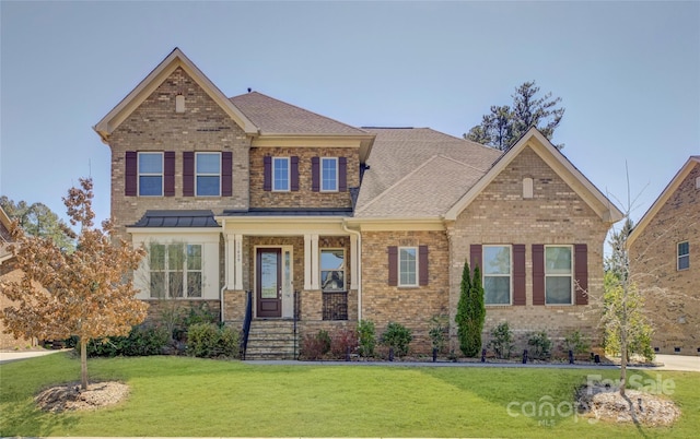 craftsman-style home with brick siding, a front yard, and a shingled roof