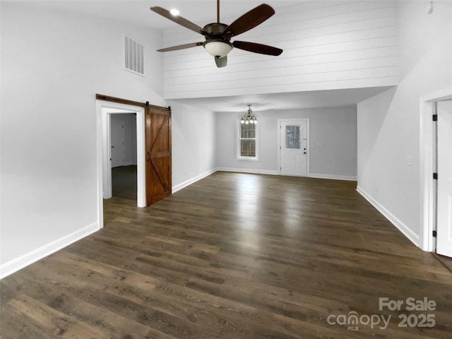 unfurnished living room with high vaulted ceiling, a barn door, visible vents, a ceiling fan, and dark wood-style floors