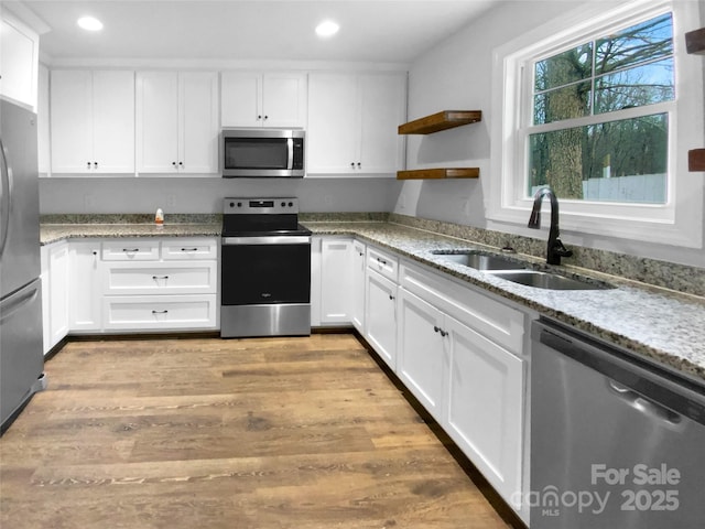 kitchen with stainless steel appliances, light wood-style floors, white cabinetry, open shelves, and a sink