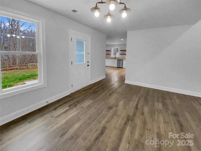 interior space with baseboards, visible vents, a chandelier, and wood finished floors