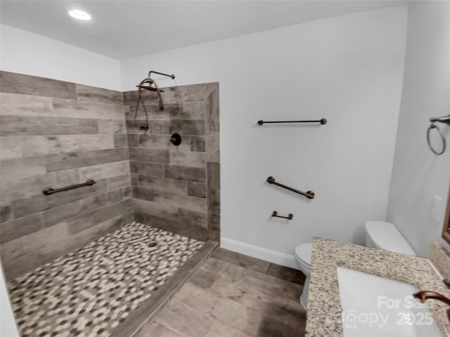 full bath with vanity, a tile shower, toilet, and baseboards