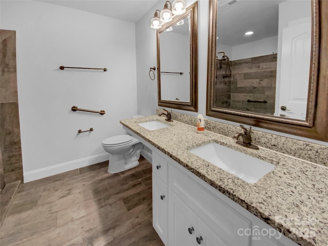 bathroom with baseboards, wood finished floors, a sink, and tiled shower