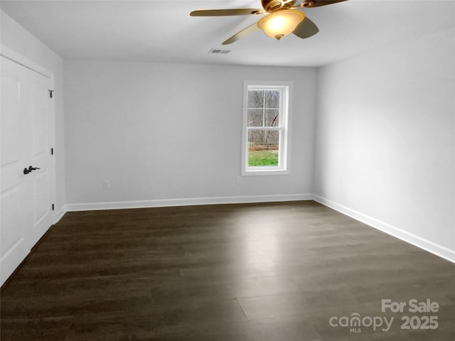 unfurnished room with dark wood-style flooring, visible vents, ceiling fan, and baseboards