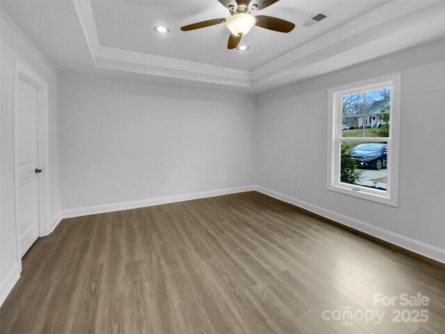 spare room with baseboards, visible vents, a tray ceiling, and dark wood-style flooring