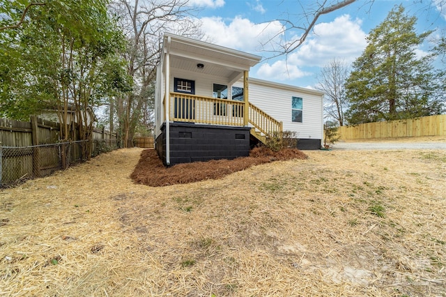 rear view of house featuring covered porch, a fenced backyard, and stairs