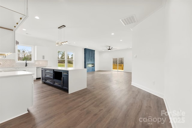 kitchen with visible vents, white cabinets, light countertops, backsplash, and dark wood-style floors