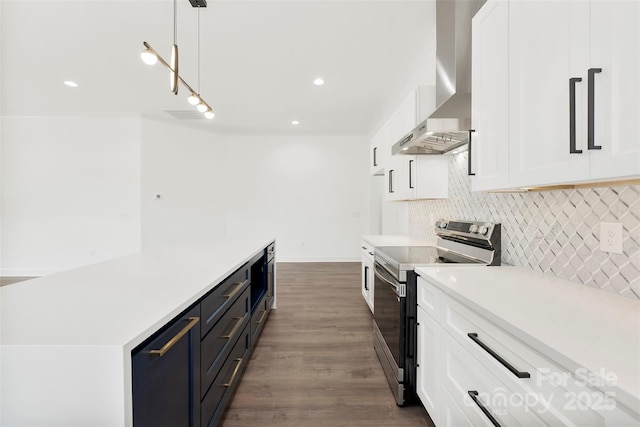 kitchen with tasteful backsplash, white cabinets, stainless steel electric range, light countertops, and wall chimney range hood