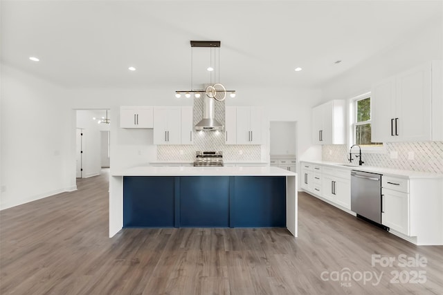 kitchen featuring stainless steel appliances, white cabinetry, and wall chimney range hood