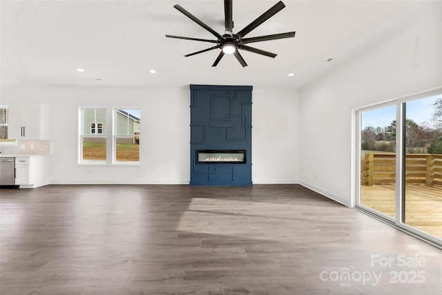 unfurnished living room featuring a large fireplace, plenty of natural light, and wood finished floors