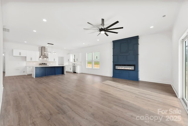 unfurnished living room featuring a ceiling fan, wood finished floors, and recessed lighting