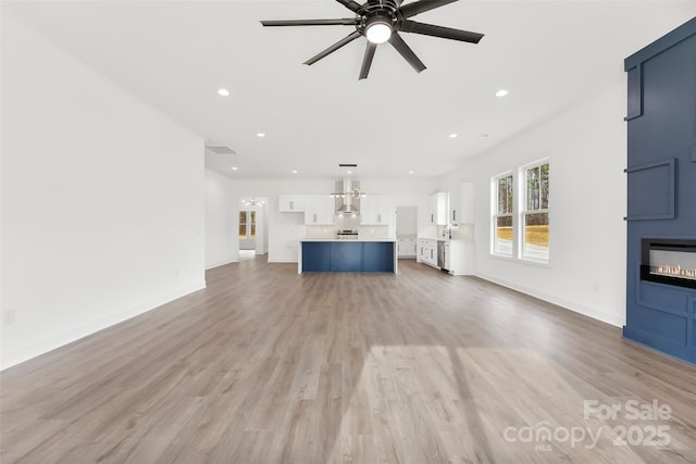 unfurnished living room with a fireplace, light wood finished floors, recessed lighting, visible vents, and a ceiling fan