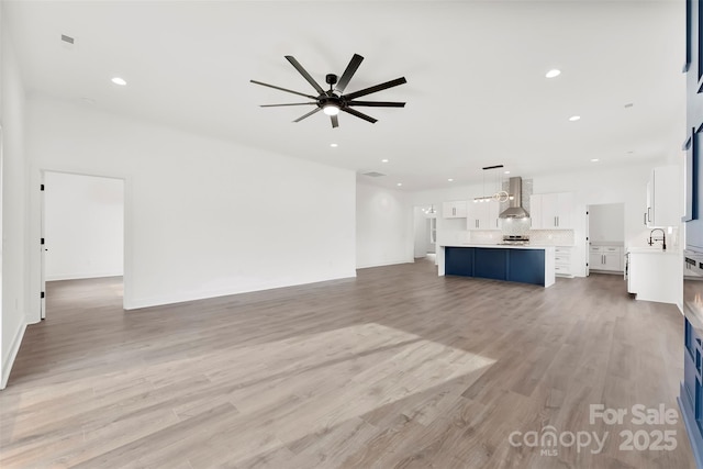 unfurnished living room with light wood finished floors, a sink, a ceiling fan, and recessed lighting