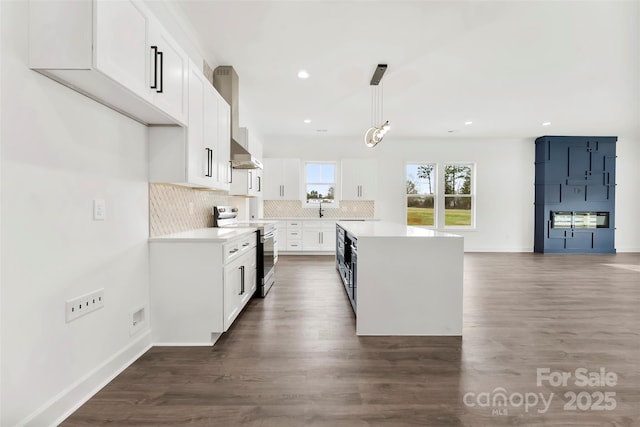 kitchen with under cabinet range hood, range with electric stovetop, light countertops, backsplash, and a center island