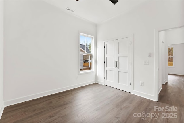 unfurnished bedroom featuring baseboards, visible vents, and dark wood-type flooring