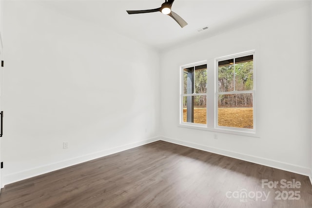 spare room featuring dark wood-style floors, visible vents, ceiling fan, and baseboards