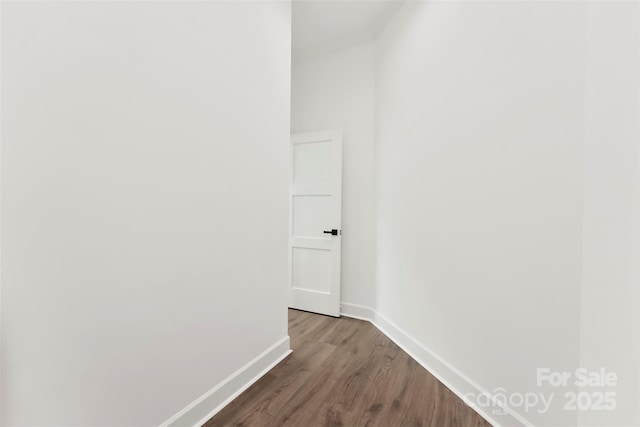 corridor featuring dark wood-style flooring and baseboards