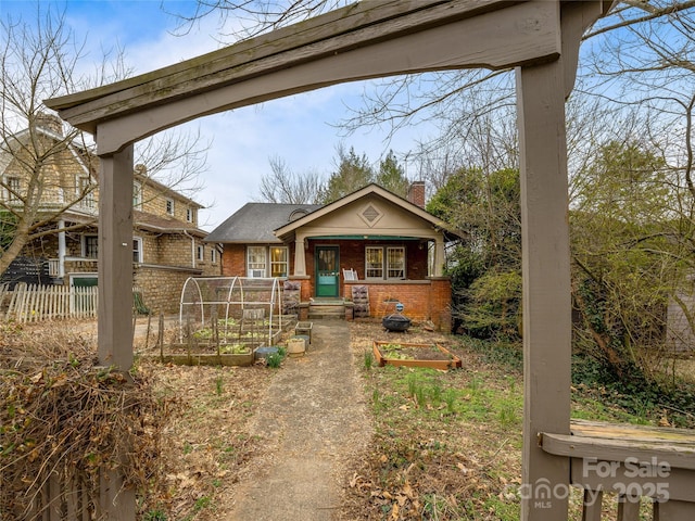 view of front of house with fence, a vegetable garden, and brick siding