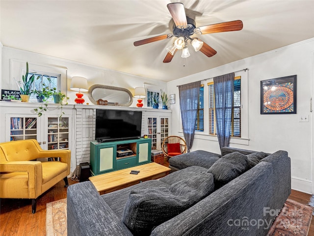 living room with a ceiling fan, crown molding, and wood finished floors