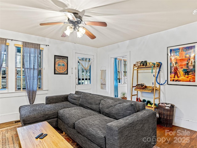 living room with baseboards, crown molding, a ceiling fan, and wood finished floors