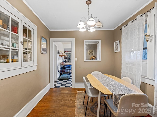 dining area featuring baseboards, ornamental molding, wood finished floors, and a notable chandelier