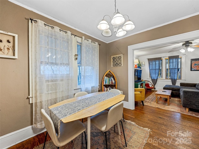 dining room featuring crown molding, baseboards, wood finished floors, and ceiling fan with notable chandelier