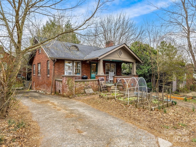 view of front of property with brick siding, a chimney, and a vegetable garden