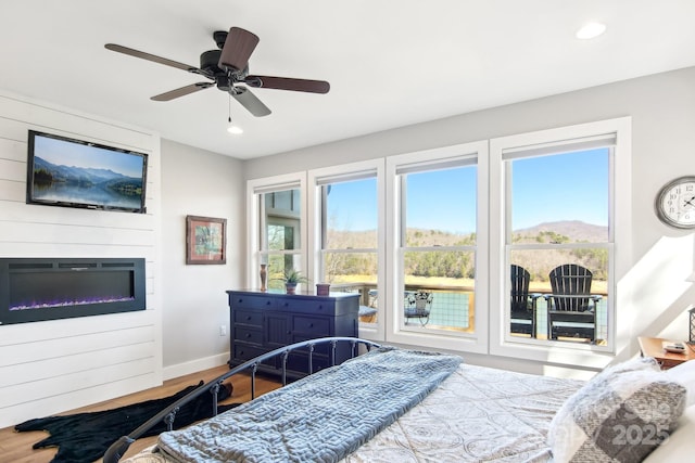 bedroom with recessed lighting, a large fireplace, ceiling fan, wood finished floors, and baseboards