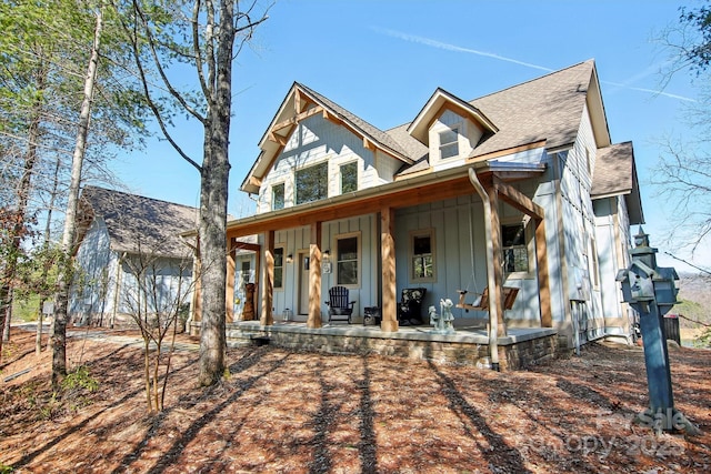 view of front facade with covered porch, a shingled roof, and board and batten siding