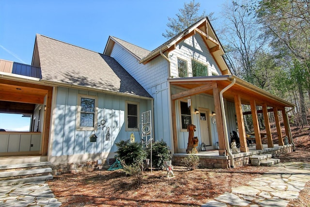 view of front facade with a porch, roof with shingles, and board and batten siding