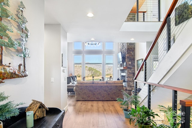 living area featuring a fireplace, wood finished floors, a towering ceiling, and recessed lighting