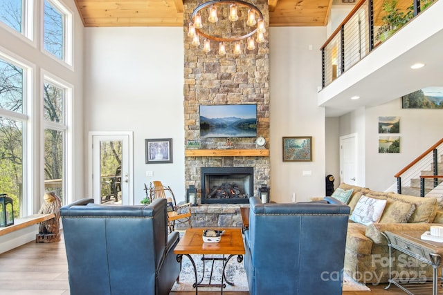 living area featuring a wealth of natural light, a fireplace, a high ceiling, and wood finished floors