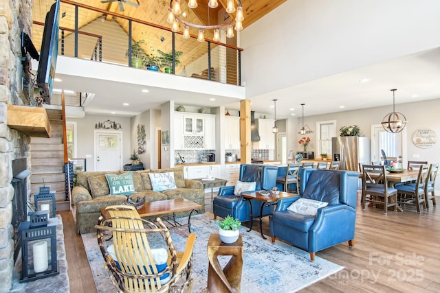 living area with light wood-style floors, recessed lighting, a high ceiling, and an inviting chandelier