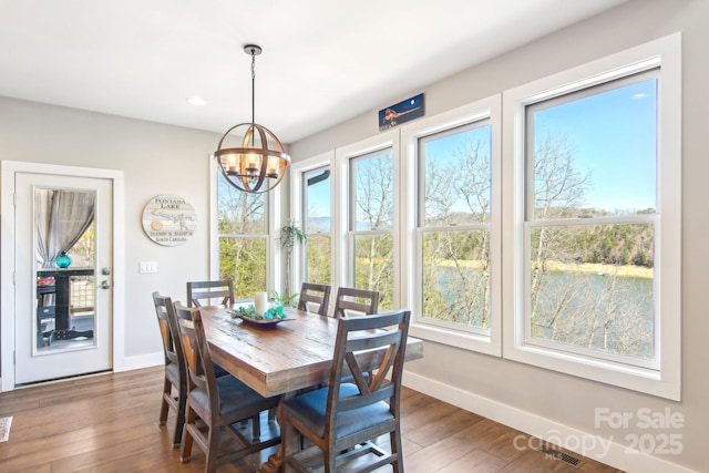 dining room featuring dark wood-style flooring, a notable chandelier, and baseboards