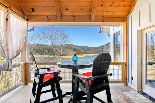 sunroom with lofted ceiling, a wealth of natural light, wooden ceiling, and a mountain view